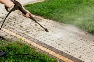 Person power washing patio pavers